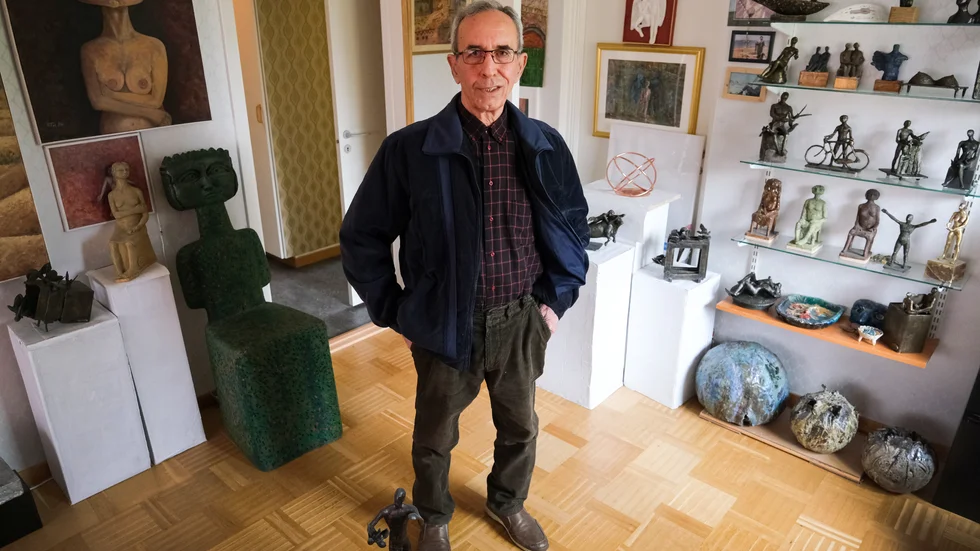 Talal Isa i sitt vardagsrum. Bokhyllorna och väggarna är fulla av egna konstverk.
