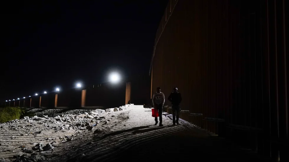 Två män närmar sig staketet längs gränsen mellan Mexiko och den amerikanska delstaten Arizona. Arkivbild.