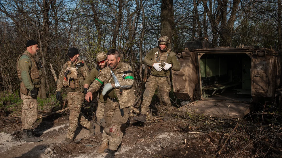 En skadad soldat har evakuerats från fronten i Bachmut i ett pansarfordon och leds iväg av sina kamrater. Bilden togs i måndags.
