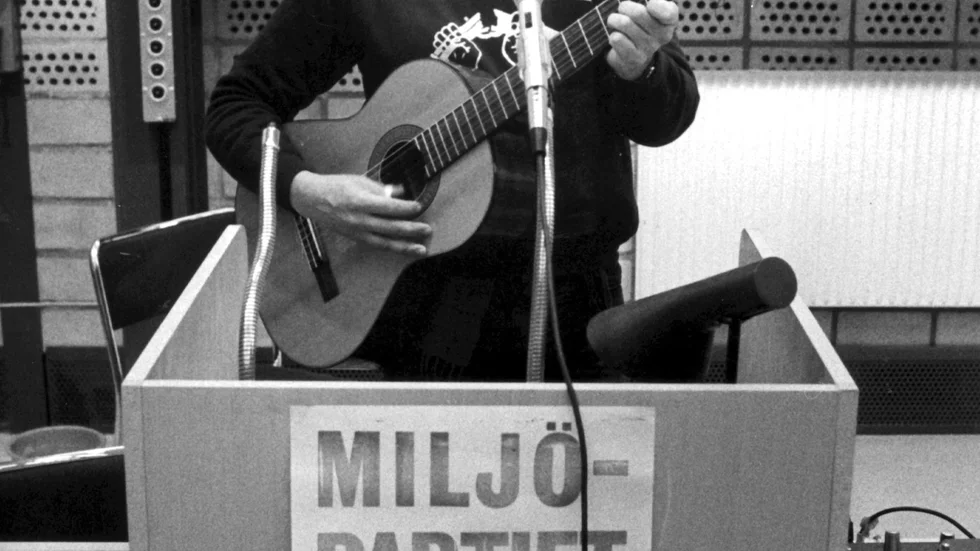 Första generationen av Miljöpartiet, här i form av trubaduren Roland von Malmborg i talarstolen med sin gitarr i december 1981.