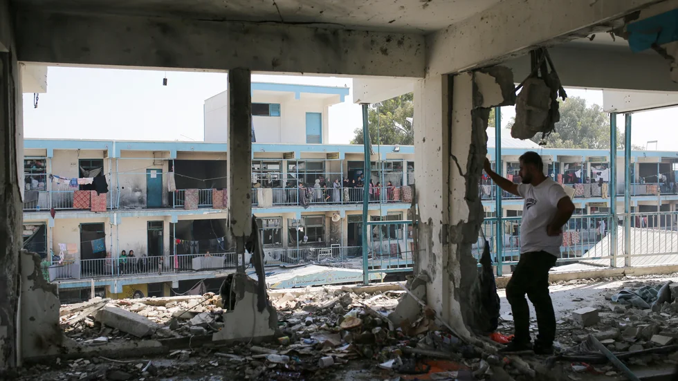 Palestinier tittar på förödelsen efter en israelisk attack mot en FN-skola i Nuseirat i torsdags.