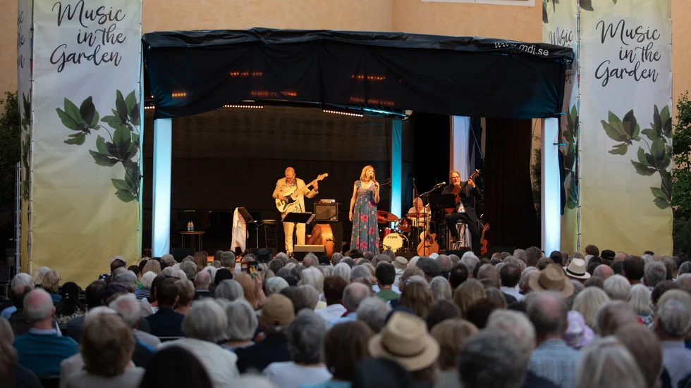 I fjol avslutades premiärkvällen av Music in the Garden med en konsert med Lill Lindfors. För ackompanjemanget stod basisten Hans Backenroth, trummisen Jocke Ekberg och gitarristen Mats Norrefalk.