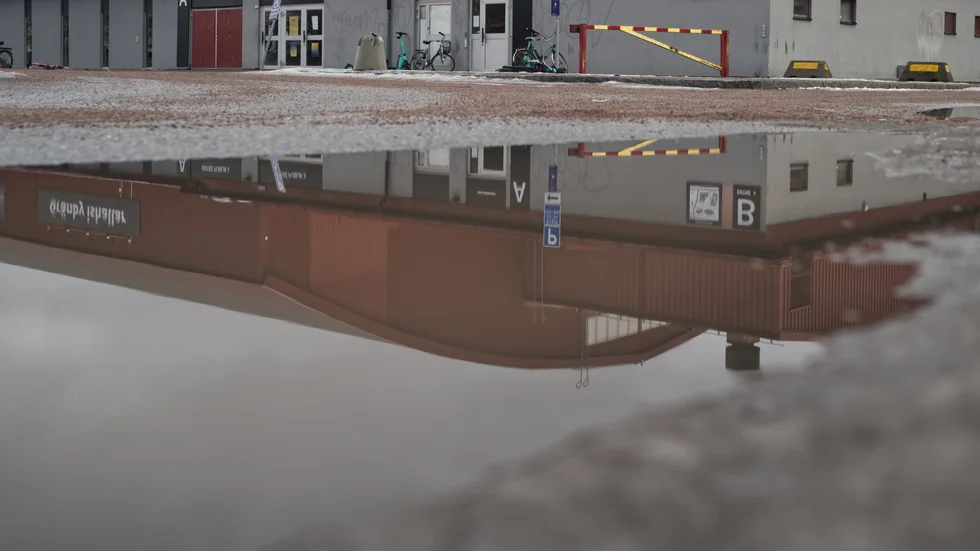 Gränbyhallens reflektion i en vattenpöl.