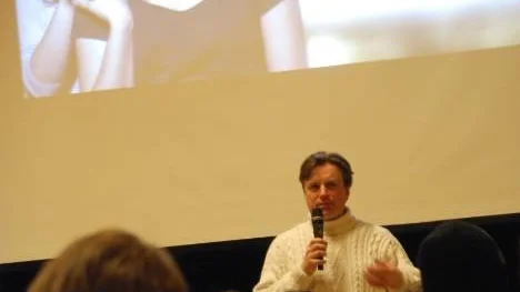 Regissören Anders Grönros i en fullsatt aula framför filmen "Jag saknar dig".