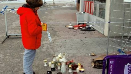 TÄNDER LJUS. En tårfylld kvinna från huset bredvid tänder en marschall utanför Johan Sandbergs kiosk - som en protest mot våldet och för att han var en trevlig människa.
