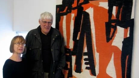 Rigmor Grönjord tillsammans med Jan Brunius framför väven "Intermezzo" som ockå bildar omslaget till biografin som presenteras i samband med dagens vernissage vid Körsbärsgården i Sundre.