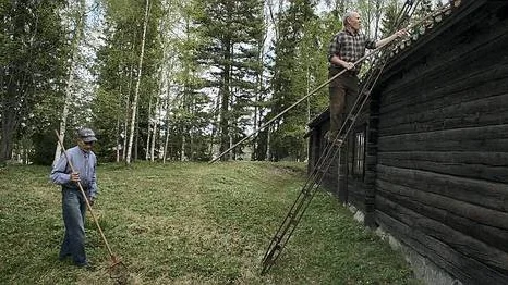 Uno Jansson borstar av ett av taken på Mörtsbogården och Sven Rönnbom krattar.