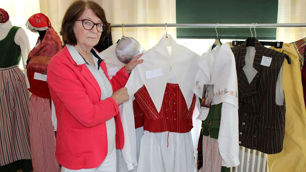 Gunilla Aronsson visar upp ett exemplar av Aspelandsdräkten som hennes mamma Lillie Svensson vävde och sydde i början av 1980-talet.