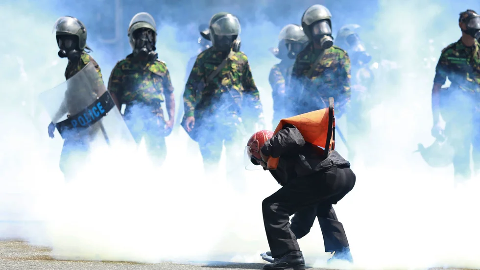 En man plockar upp en tårgasbehållare för att kasta den efter att polisen avfyrat den för att skingra demonstranterna i Sri Lankas huvudstad Colombo.