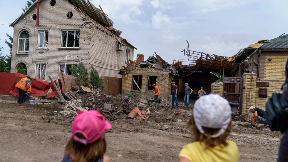 Barn ser på när räddningsmanskap går igenom skadorna efter en granatattack i Kramatorsk i östra Ukraina. Inga personer skadades i attacken i fredags.