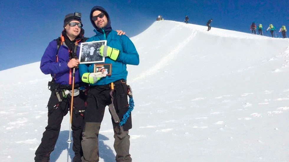 Nicklas Lautakoski och Christoffer Andersson på Kebnekaises topp, med en bild på sin vän. Solen bröt igenom molnen precis när de nådde toppen.