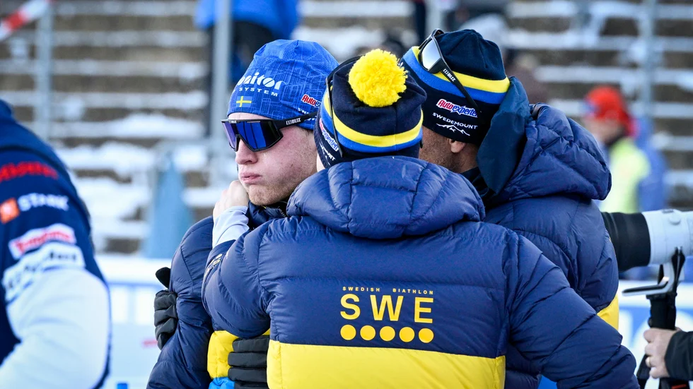 Sveriges Sebastian Samuelsson (vänster) grät och tröstades av tränarna Jean-Marc Chabloz (höger) och Johannes Lukas efter målgång i onsdagens mixedstafett.