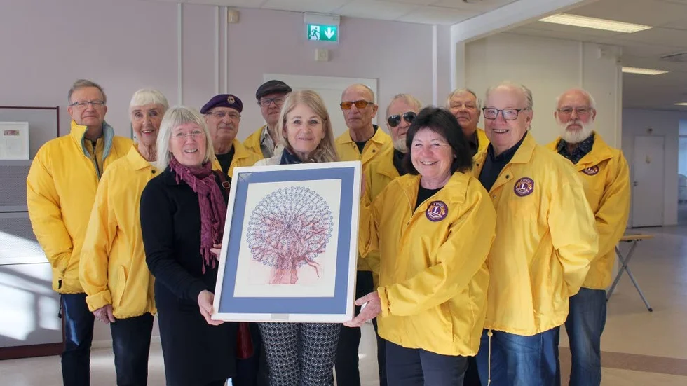 Eva-Lena Djerf, i mitten, tar emot ett konstverk som konstnären My G. Eriksson, till vänster, har gjort. På bilden ses också representanter för Lions Club Norra Tjust.