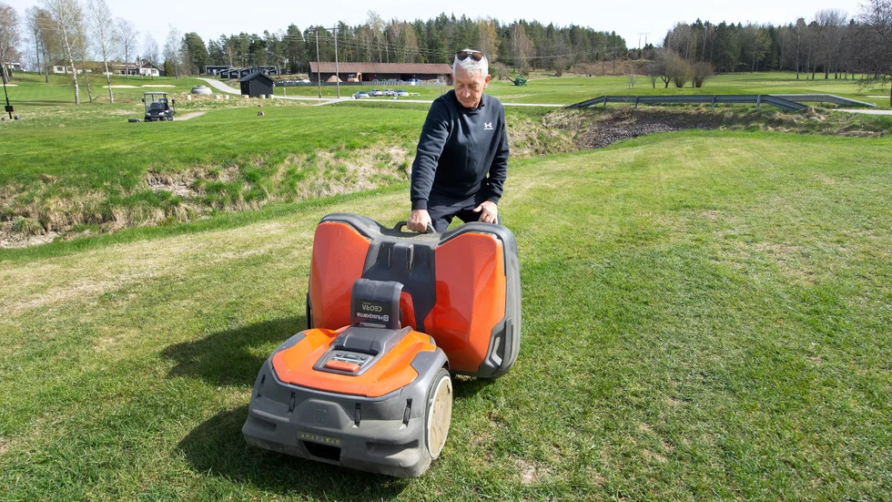 John Ekoff, vice ordförande i Nyköpings GK, vid en av de stora robotgräsklipparna på den Västra banan.