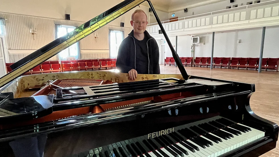 Zacharias Kärnekull Wolfe från föreningen Hjorted Art and Music beundrar den nya flygeln som numera står i Folkets Hus i Ankarsrum.
