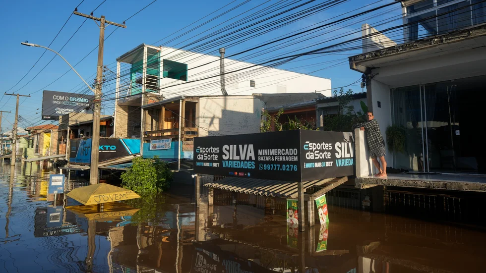 A resident stands on the balcony of his home partially submerged by flood waters from heavy heavy rains, in Porto Alegre, Rio Grande do Sul state, Brazil, Thursday, May 9, 2024.