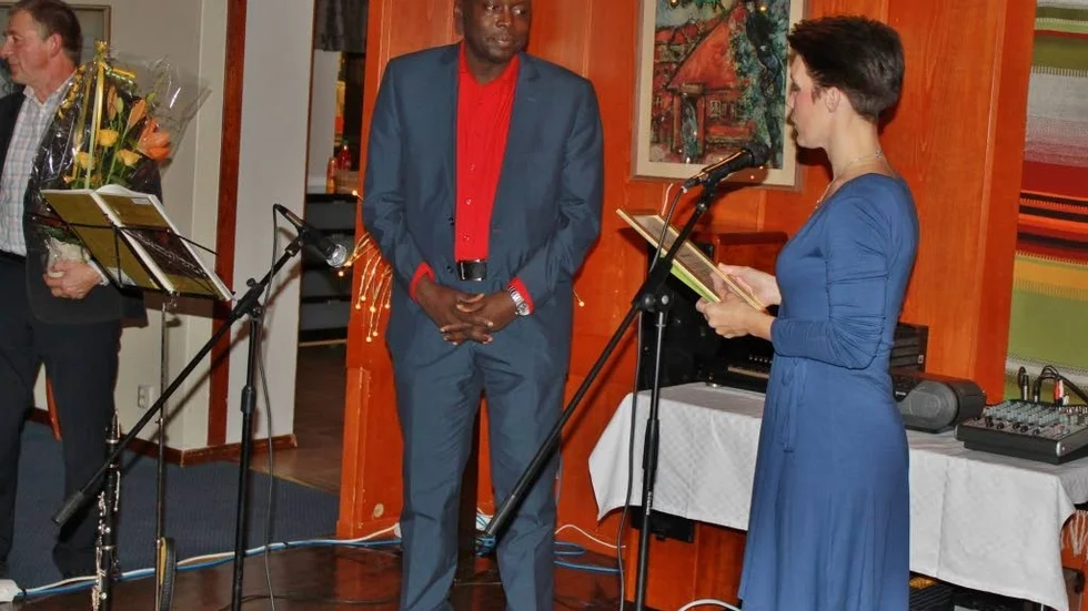 HYLLAD AV CENTERN. Årets ledarstipendiat Michel Ntoto. Till höger Matilda Viklund och till vänster står Stefan Hardselius beredd med blomuppsättning.