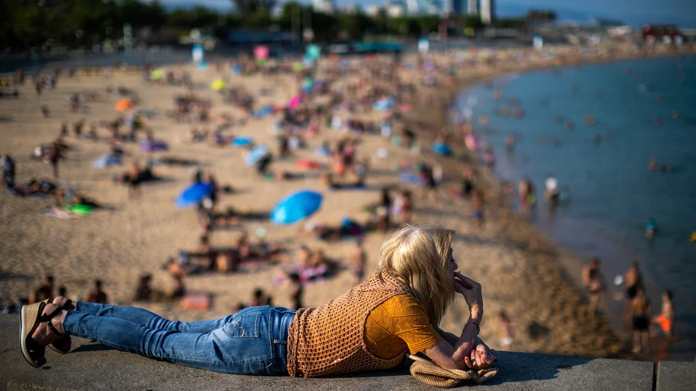 En kvinna tar en cigarett vid en strand i Barcelona i Spanien. Snart måste solbadare fimpa innan de tar plats i sanden i staden. Arkivbild.