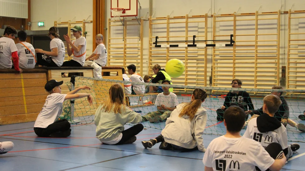 Sex mot sex spelar barnen volleyboll, fast sittande med en jättestor boll. 