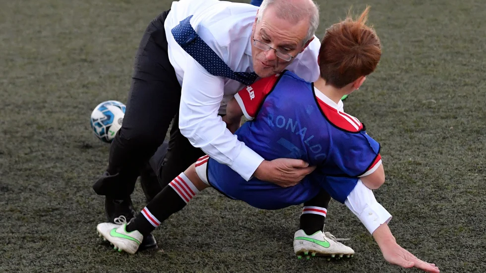 Australiens premiärminister Scott Morrison tacklar en pojke under en fotbollsmatch under valkampanjandet på onsdagen.