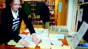Trångt. Valsedlarna för de olika partierna och valen är många och några kan försvinna i mängden. Charlotte Andersson passar på att snygga till  när antalet röstande i lokalen inte är så många. Foto: MATILDA AHL