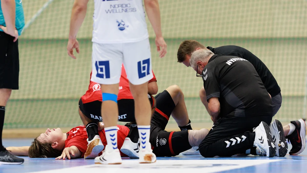 Johan Palm ligger på golvet i Kungsbacka sporthall och får sitt skadade knä lindat.