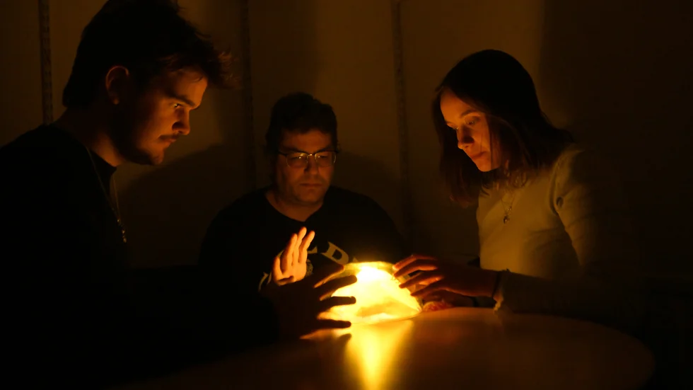 Mille Dybro, Adam Savonen och Johanna Salo tittar in i spåkulan. 