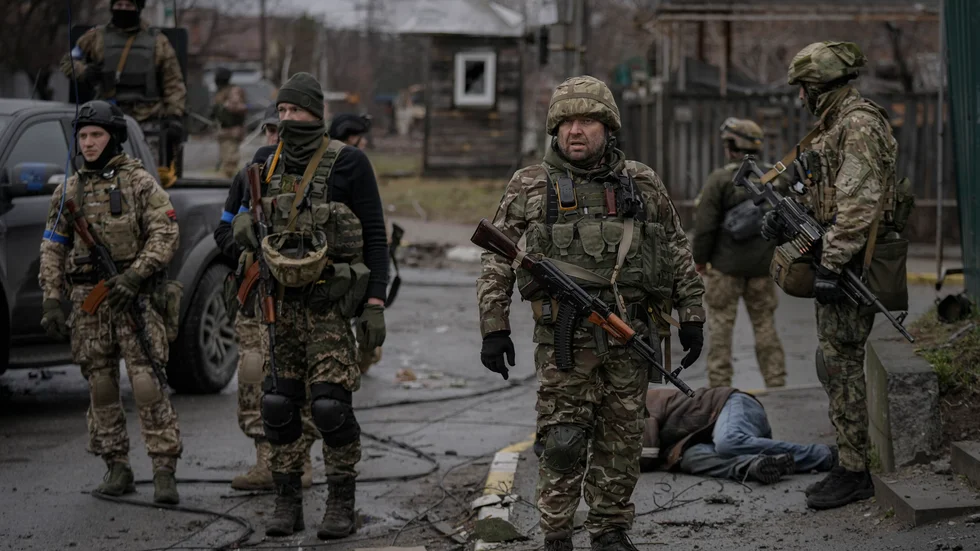 Ukrainsk militär i staden Butja efter den ryska reträtten. Ryssland anklagas för krigsbrott efter att döda civila hittats på gatorna.