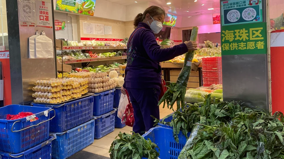 En kvinna i Kanton-provinsen handlar mat under torsdagen sedan en affär öppnat efter de lättade restriktionerna.
