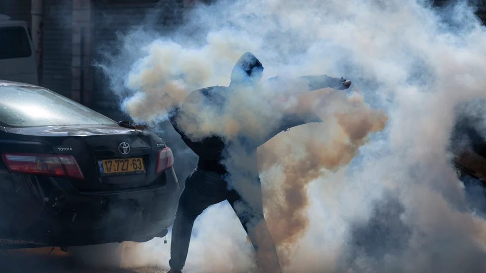 En palestinsk demonstrant kastar tillbaka en tårgasbehållare mot israeliska soldater i en drabbning den 27 december. Arkivbild.