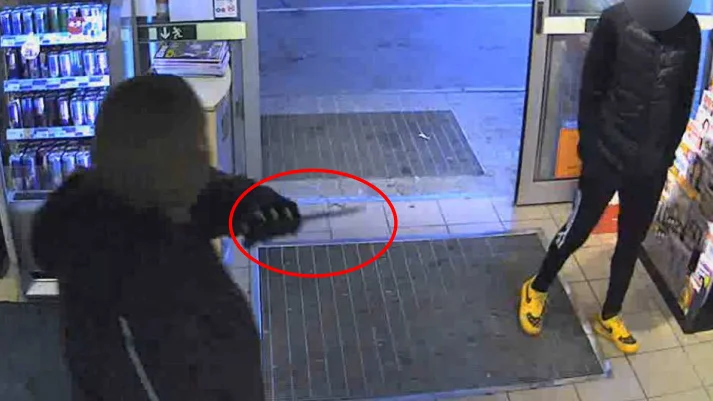 Bilden visar när mannen hotar en kund inne på bensinstationen.