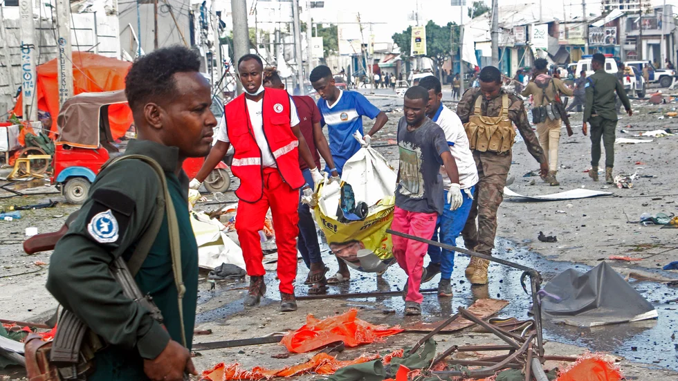 Kvarlevor lyfts bort vid den drabbade korsningen i centrala Mogadishu på lördagen.