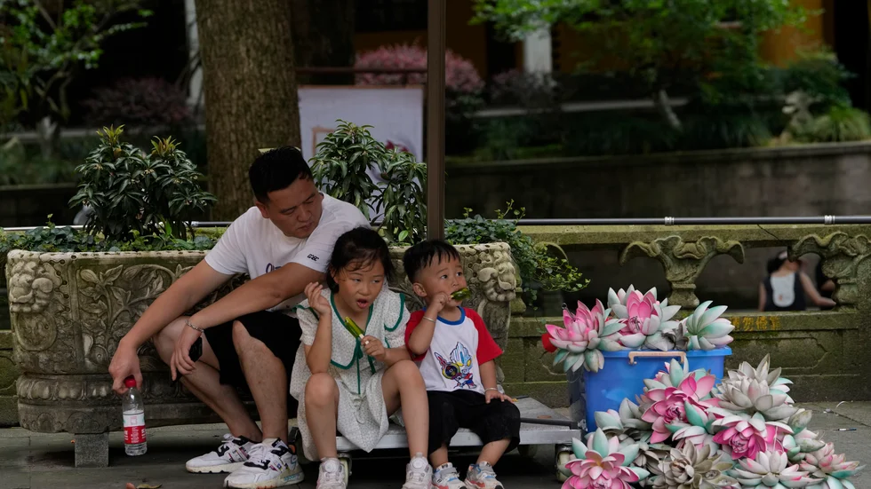 Barn svalkar sig i skuggan i Hangzhou i östra Kina.