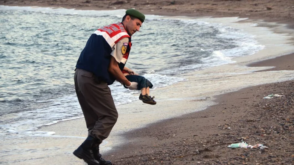 Den här bilden på polistjänstemannen som varsamt tar Alans lilla kropp i sin famn, spred sig som en löpeld på sociala medier och blev förstasidesstoff på flera av världens största tidnin
