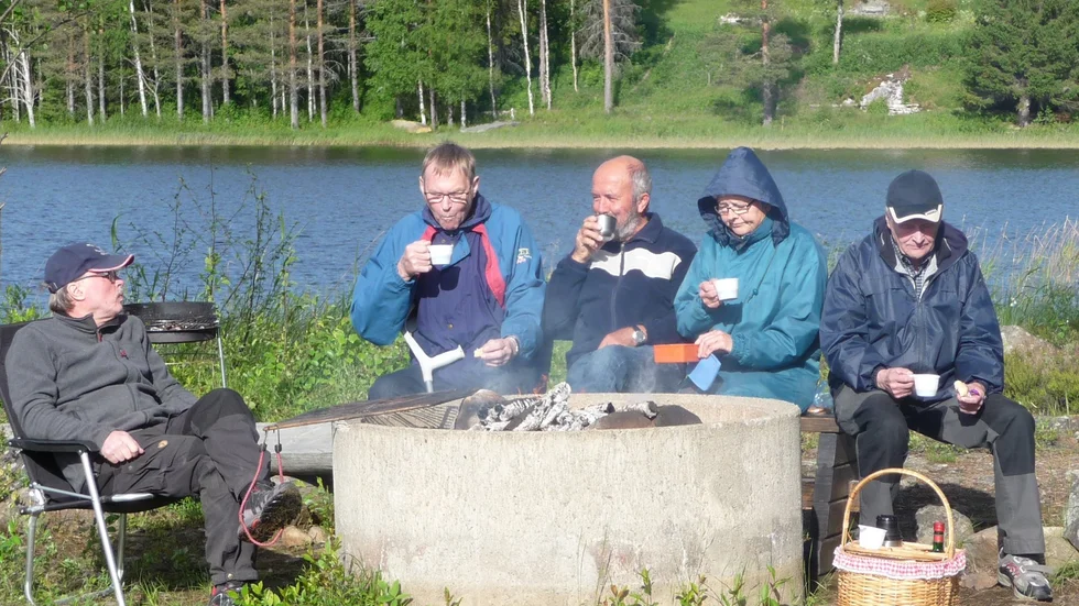 Värmde gott. Ansgar Olofsson, Roy Karlsson, Göte Olofsson, Viola Karlsson och Gunnar Löfstedt värmer sig med en kopp kaffe.