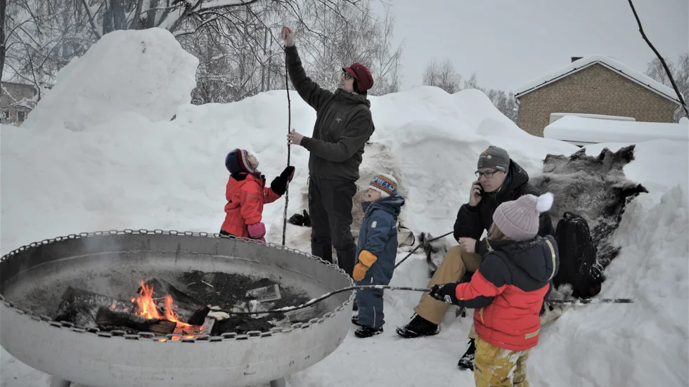 Pappa Markus hjälper dottern Linnea med korv och pinne under överinseende av sonen Nils, Mattias Berglund och hans dotter Áilá-Sofe.