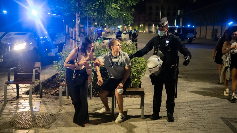 Arkivbild på en lokalpolis som föser undan två personer från en partygata i Barcelona.