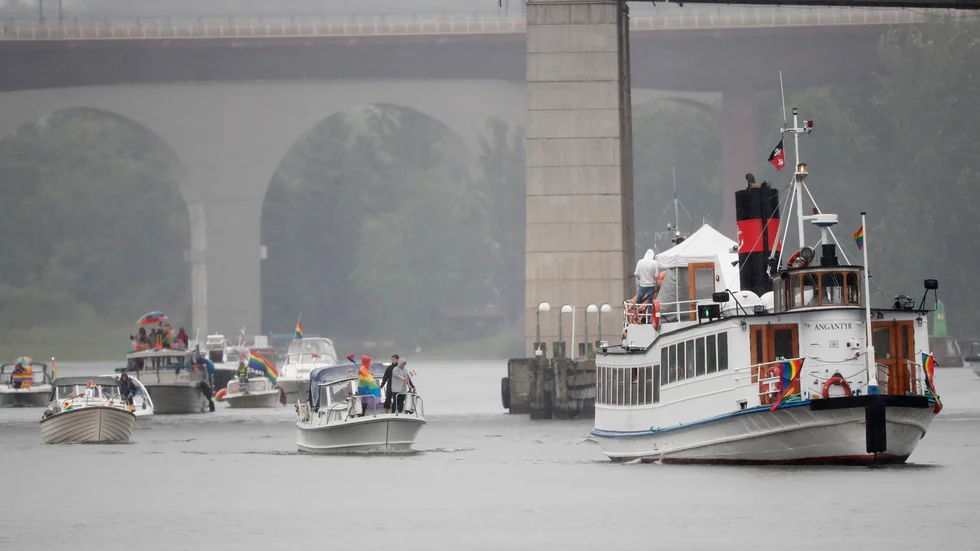 Båtar i ösregn tar sig ut i en prideparad från Årstaviken, under Liljeholmsbron, mot Riddarfjärden i Stockholm.