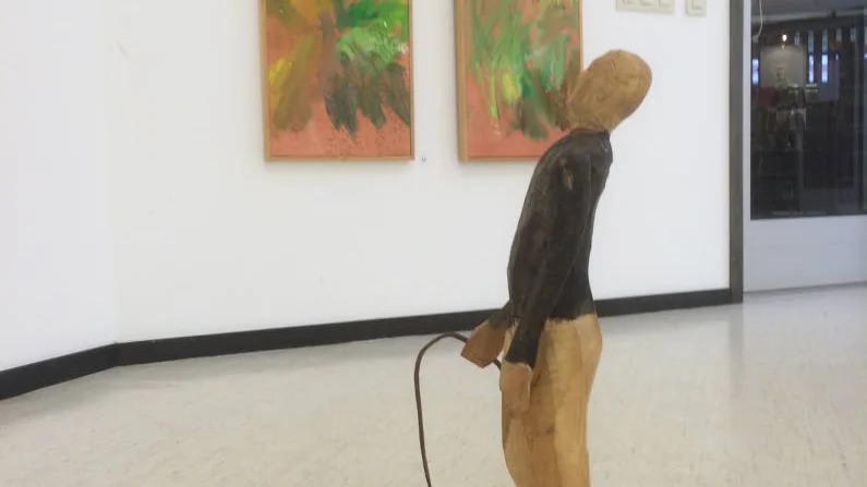 "Väntan”, träskulptur av Per Josefsson (i bakgrunden de två målningarna ”Smedjan och ”Ladan”).