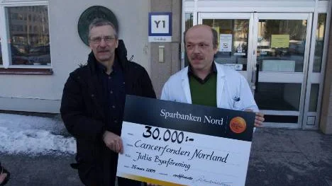 Jutis byaförenigns representant Rolf Westerlund överräcker 30 000 kronor till Roger Henriksson, professor och överläkare vid onkologiska kliniken vid Norrlands univeristetssjukhus i Umeå.