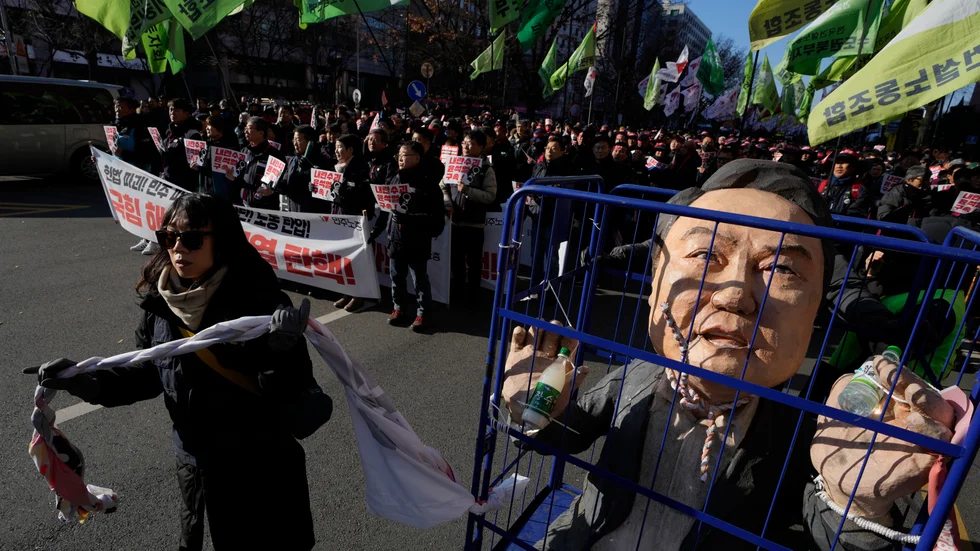 En kvinna drar en docka föreställande Sydkoreas president Yoon Suk-Yeol bakom galler. Bilden togs under de protester mot den kritiserade presidenten som pågår i Seoul.