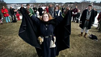 Vårblot i Gamlis. Cajsa Falk sträcker armarna i luften under ceremonin i Gamla Uppsala.
