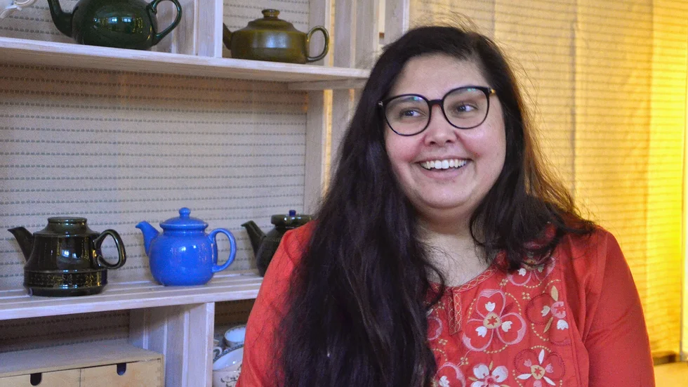 Sangeeta sitter på kuddar i den lilla tehörnan i sin lokal.