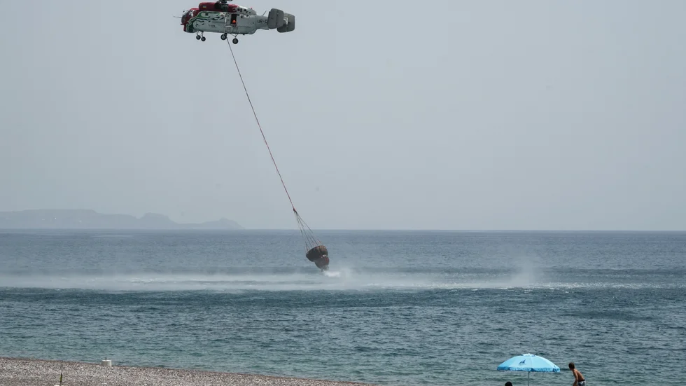 En helikopter som samlar upp vatten för att bekämpa en skogsbrand på Rhodos den 27 juli.
