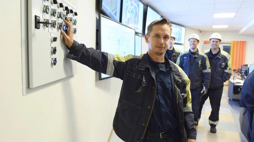 Projektledare Daniel Westerlund trycker på knappen som öppnar huvudvarmblästerventilen, vilken förser ugnen med blästerluft.  Bakom honom syns f.v Jonas Lövgren, Patrik Midebjörk och Björn Ek.