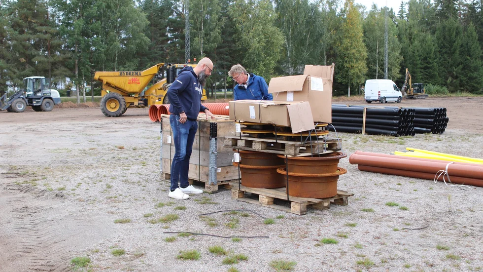 Patrick Schönfeldt och Patrick Edrenius tittar i den senaste leveransen och konstaterar att det är brunnarna som kommit till den nya konstgräsplanen.