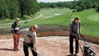 Byggledaren Lars Mattsson från Västervik kontrollerar att Malin Hultin och Alexander Feinestam får ordning på bunkern intill första hålet.
Foto: INGEMAR PETERSSON