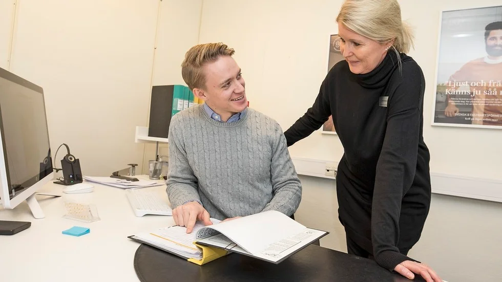 Felix Mejman och Cecilia Fredriksson går igenom några handlingar runt en husförsäljning. Yngst och äldst på jobbet i glatt samspråk.