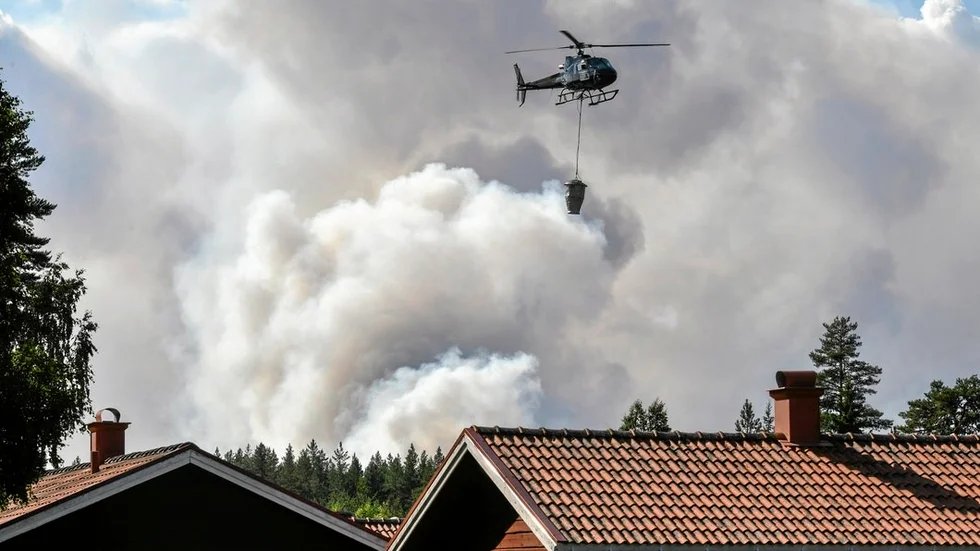 En helikopter hjälper till med släckningsarbetet vid en skogsbrand nära Färila, Ljusdal.