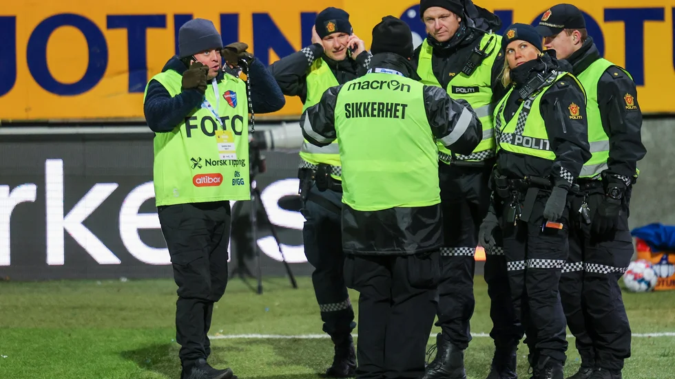 NTB:s fotograf Trond Rediar Teigen, till vänster, i samtal med polisen sedan en supporter urinerat på honom under en match i norska ligan i helgen.